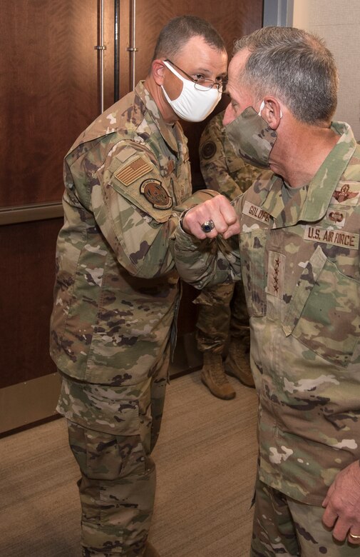 Photo of Air Force Chief of Staff Gen. David L. Goldfein, elbow bumping Master Sgt. Robert Crowe, a branch superintendent for A6 in Air Force Reserve Command, after giving him a coin for his contributions in boosting teleworking capabilities during the COVID-19 pandemic at Robins Air Force Base, Georgia, June 24, 2020.