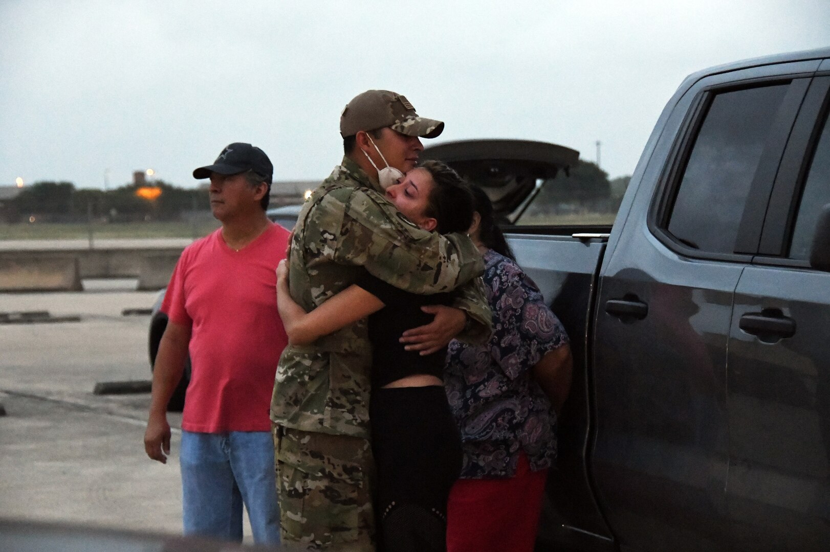 Senior Airman Rene Ruiz, 433rd Civil Engineer Squadron firefighter, hugs his girlfriend, Angelica Cabuto, while his parents stand nearby June 28, 2020, at Joint Base San Antonio-Lackland, Texas.