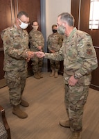 Photo of Air Force Chief of Staff Gen. David L. Goldfein, giving a coin to Master Sgt. Robert Crowe, a Branch Superintendent for A6 in Air Force Reserve Command, for his contributions in boosting teleworking capabilities during the COVID-19 pandemic at Robins Air Force Base, Georgia, June 24, 2020.