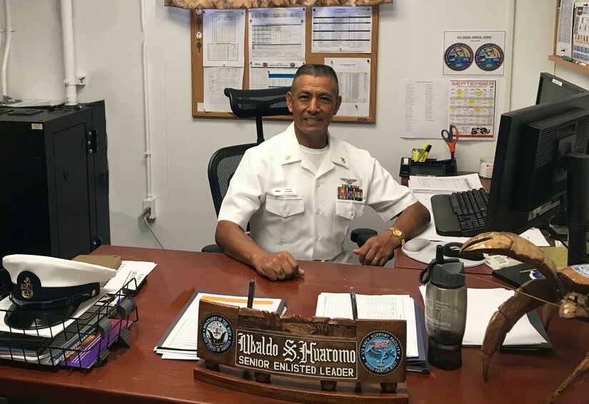 A sailor sits behind a desk.