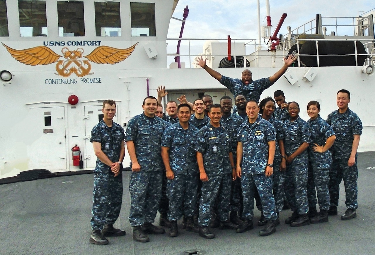 A group of sailors stands on the deck of a ship.