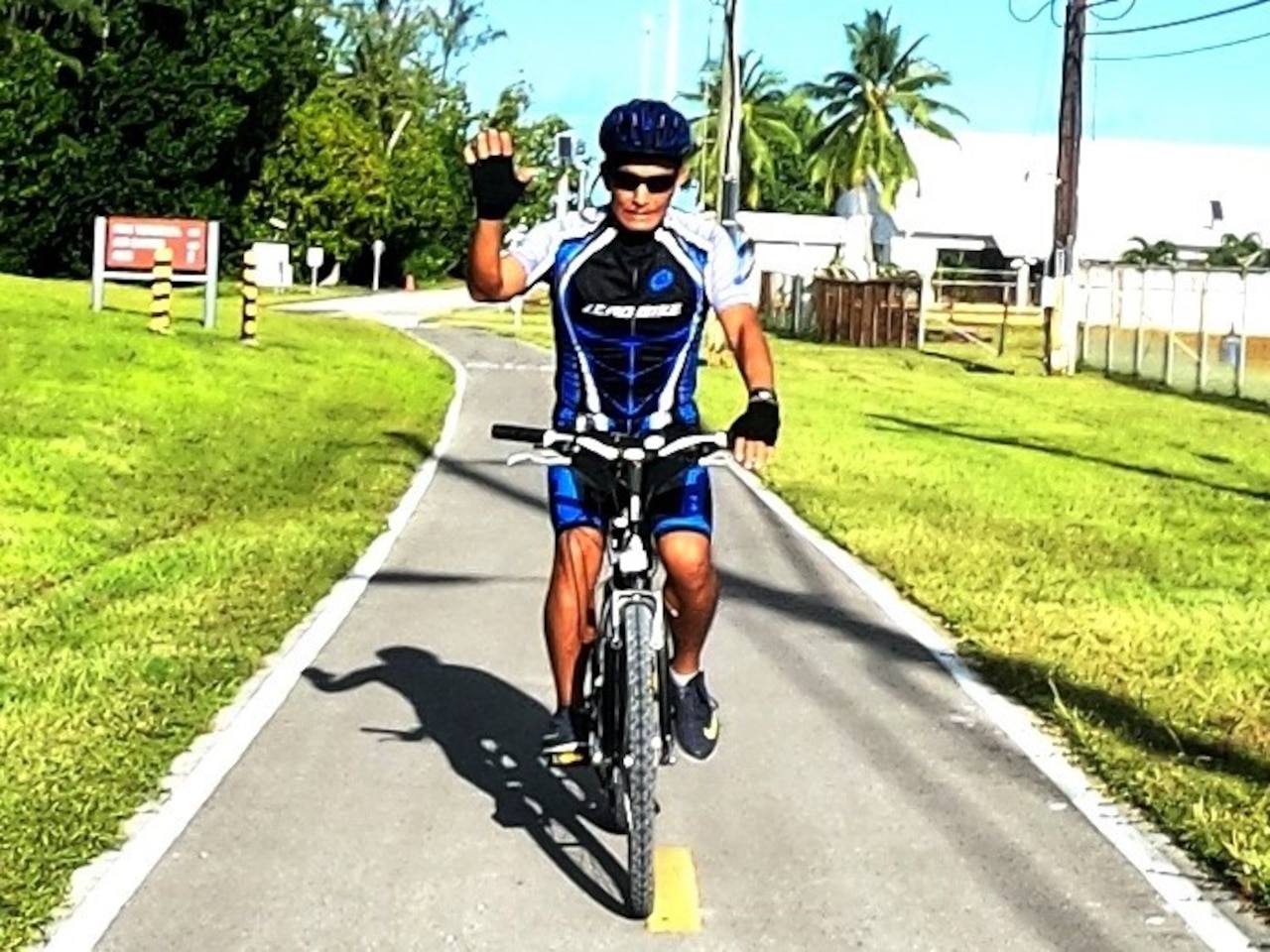 A man wearing a bicycle helmet and gear rides a bike on a path.