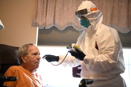 Staff Sgt. Kathryn Dobbs, an aerospace medical technician assigned to the 180th Fighter Wing, takes the temperature of an asymptomatic COVID-19 positive resident May 27, 2020, at the Carlin House in Logan, Ohio. Dobbs was part of a 20-person tOhio National Guard team that helped at the assisted living facility after over half the staff and residents tested positive for COVID-19.