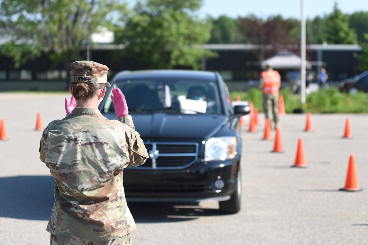 A soldier directs traffic at a COVID-19 drive-thru test site.