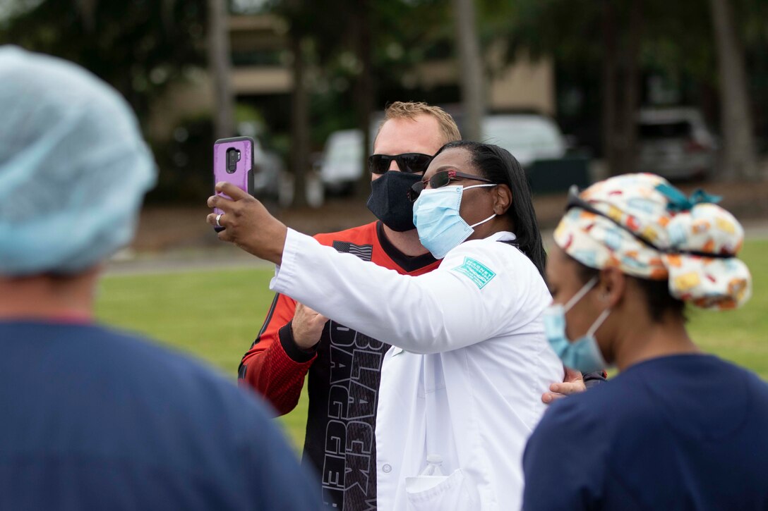 A medical worker takes a selfie with a member of a military parachute team.