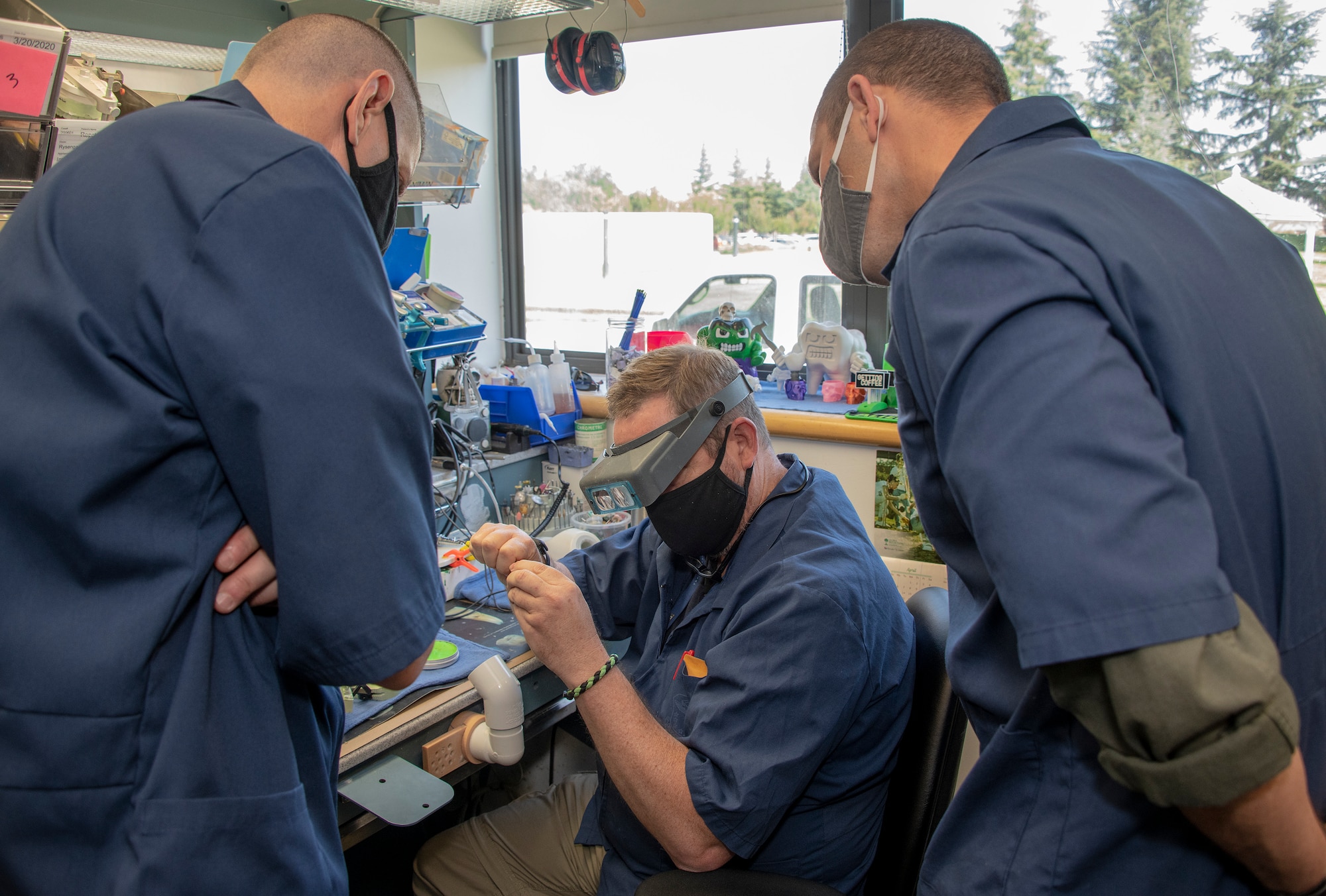 U.S. Air Force Chief Master Sgt. Derek Crowder, left, 60th Air Mobility Wing command chief, and Col. Zachery Jiron, 60th AMW vice commander, right, watch Robert Silva, center, 60th Dental Squadron dental laboratory technician create a wax mold for a dental crown during Leadership Rounds June 26, 2020, at David Grant USAF Medical Center, Travis Air Force Base, California. The Leadership Rounds program provides 60th AMW leadership an opportunity to interact with Airmen and get a detailed view of each mission performed at Travis AFB.  (U.S. Air Force photo by Heide Couch)