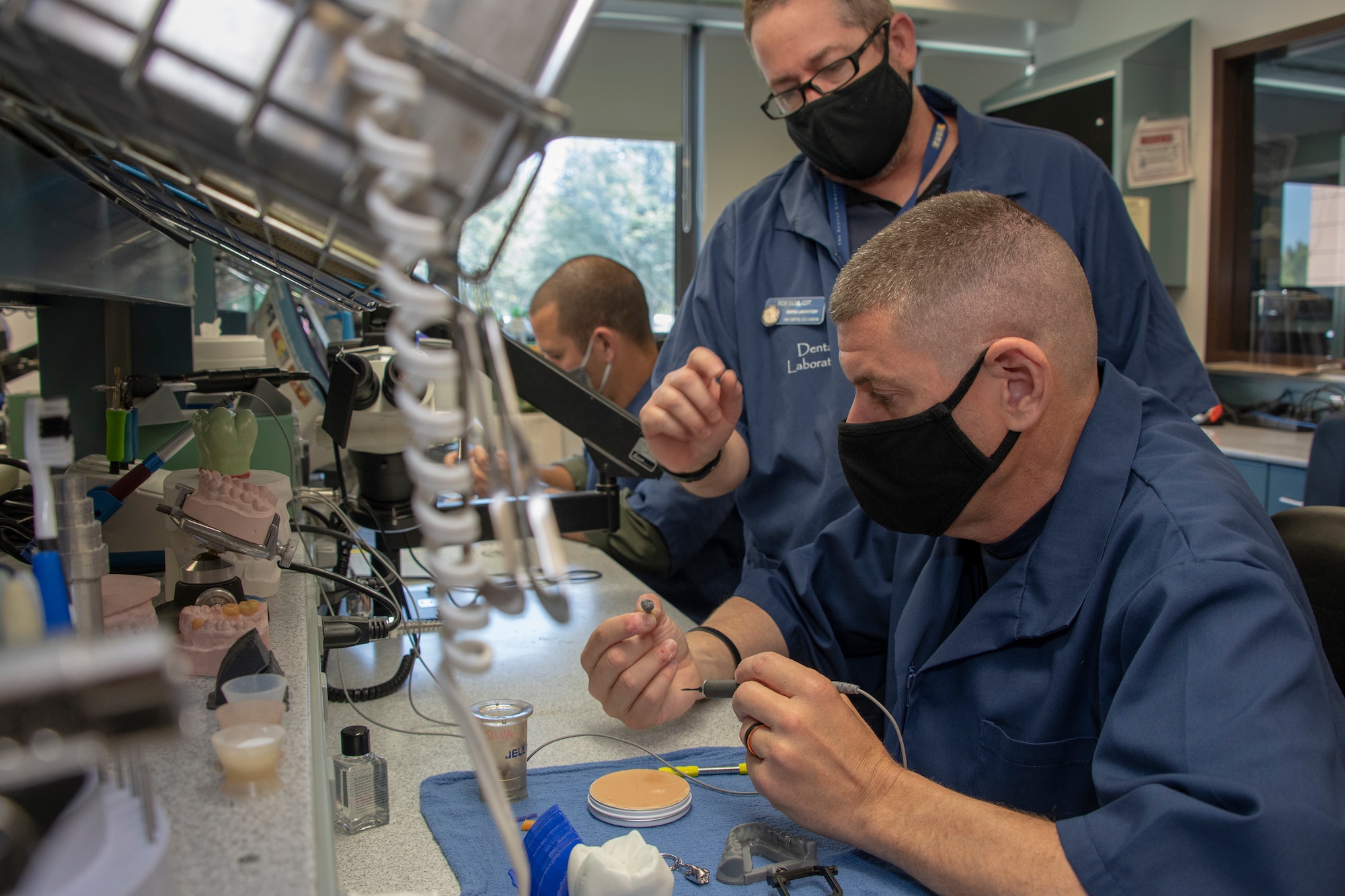 U.S. Air Force Chief Master Sgt. Derek Crowder, right, 60th Air Mobility Wing command chief, uses wax to create a dental crown mold while Robert Silva, 60th Dental Squadron dental laboratory technician watches during Leadership Rounds June 26, 2020, at David Grant USAF Medical Center, Travis Air Force Base, California. The Leadership Rounds program provides 60th AMW leadership an opportunity to interact with Airmen and get a detailed view of each mission performed at Travis AFB.  (U.S. Air Force photo by Heide Couch)