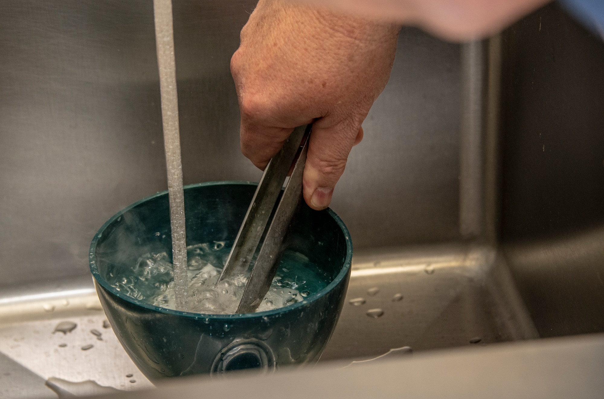 Robert Silva, 60th Dental Squadron dental laboratory technician cools down a dental crown casting during Leadership Rounds June 26, 2020, at David Grant USAF Medical Center, Travis Air Force Base, California. The Leadership Rounds program provides 60th AMW leadership an opportunity to interact with Airmen and get a detailed view of each mission performed at Travis AFB.  (U.S. Air Force photo by Heide Couch)
