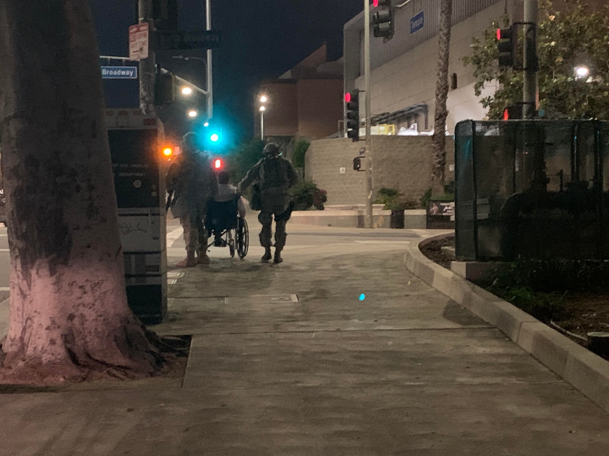 U.S. Air National Guard Tech. Sgt. Omar Godoy and Master Sgt. Jordan Kennedy from the California Air National Guard's 146th Airlift Wing's Security Forces Squadron, assist with transporting a elderly pedestrian by pushing his wheelchair up Temple Ave in Los Angeles, California. June 1, 2019. Courtesy photo by California Military Department.