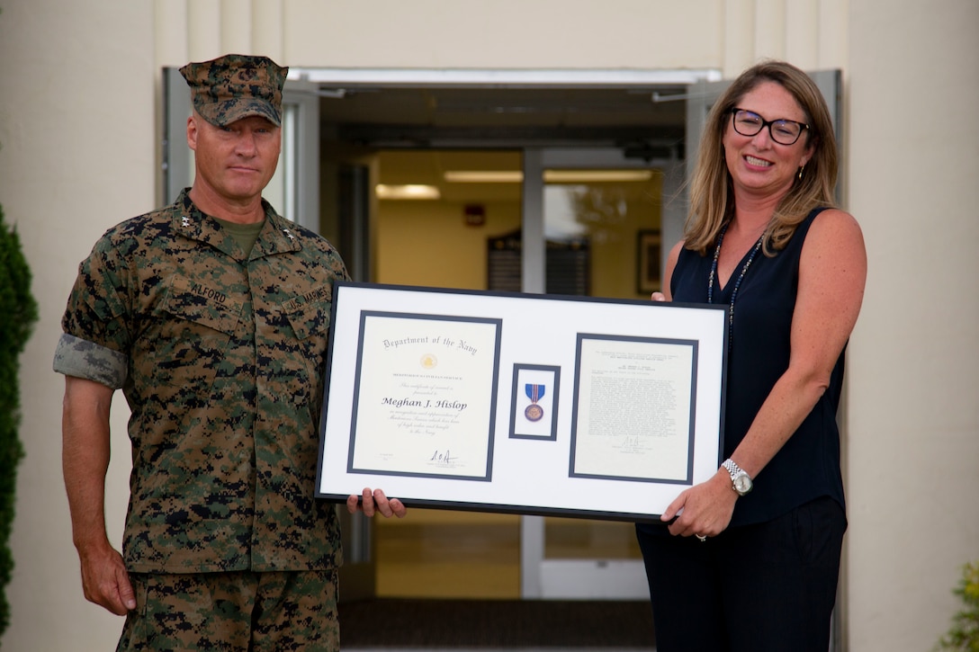 Meghan Hislop, right, acquisition division director, Naval Facilities Command (NAVFAC) Office in Charge of Construction-Florence, receives the Department of the Navy Commendation for Meritorious Civilian Service from Maj. Gen. Julian D. Alford, left, commanding general, Marine Corps Installations East-Marine Corps Base Camp Lejeune, at the Public Works Office on MCB Camp Lejeune, North Carolina, June 30, 2020. Hislop received the award for her efforts in coordinating a multibillion dollar restoration and construction program in the wake of Hurricane Florence. (U.S. Marine Corps photo by Lance Cpl. Ginnie Lee)