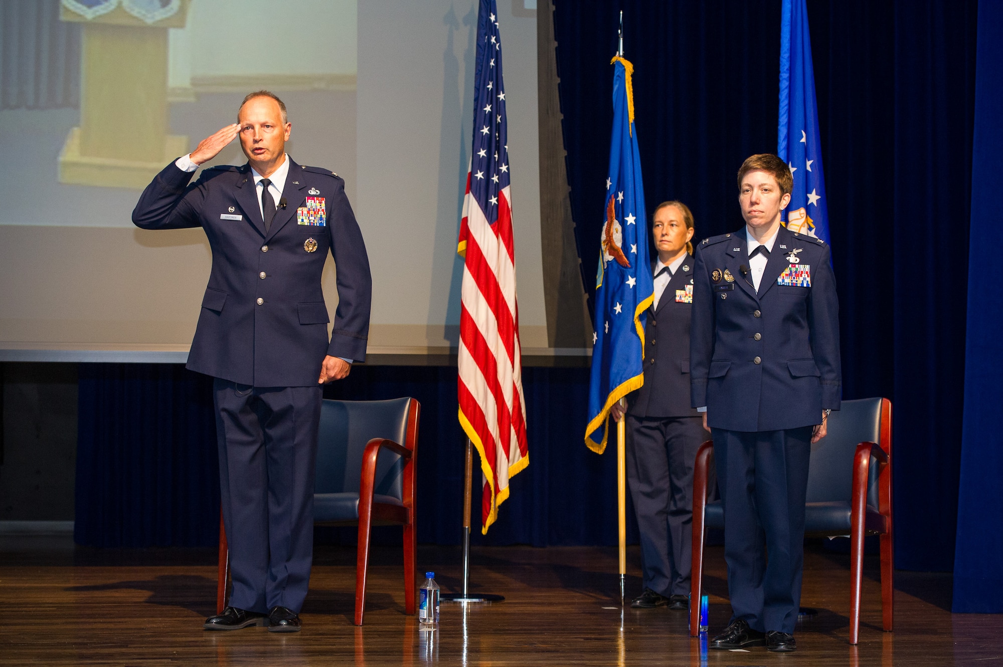 Col. Chad Hartman (left), commander of the Air Force Technical Applications Center, Patrick AFB, Fla., salutes and relinquishes command during a Change of Command ceremony June 30, 2020 as his replacement, Col. Katharine Barber (right) stands at attention.  Also pictured is guidon bearer Chief Master Sgt. Amy Long (center), AFTAC’s command chief.  (U.S. Air Force photo by Amanda Ryrholm)