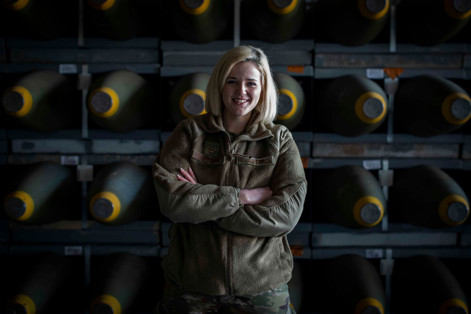 U.S. Air Force Airman 1st Class Autumn Gregory, 86th Munitions Squadron munitions stockpile management technician, poses for a photo in front of a stockpile of munitions at Ramstein Air Base, Germany, Feb. 6, 2020. The 86th Munitions Squadron received more than 200 crates of various munitions and inert components to be distributed to combatant commands in the region. (U.S. Air Force photo by Staff Sgt. Devin Nothstine)