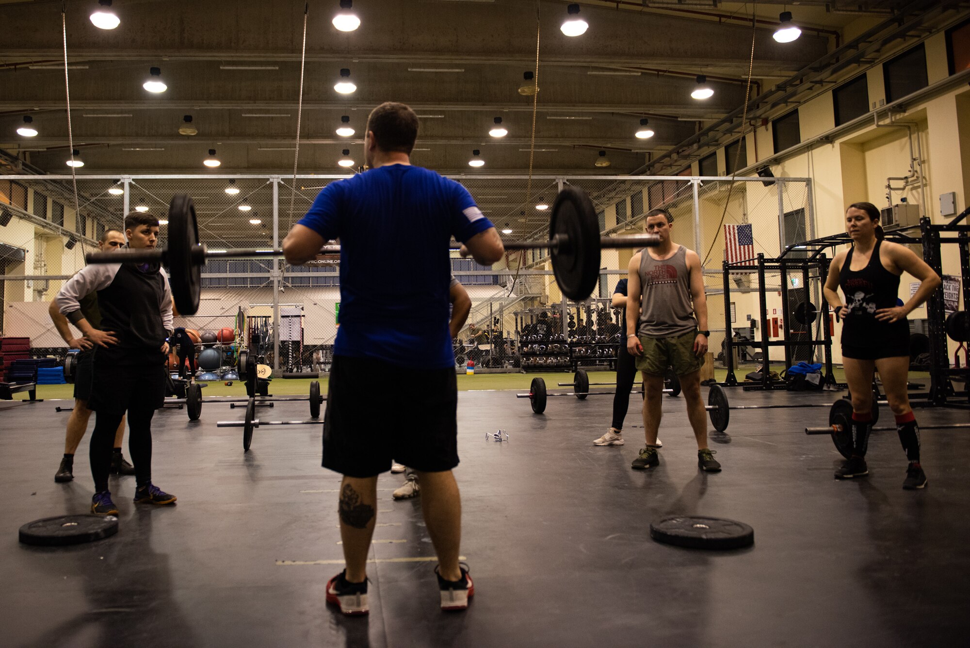 U.S. Air Force Senior Airman Eric Cooke, weapons director with the 606th Air Control Squadron and volunteer CrossFit coach, demonstrates proper technique to a CrossFit class at the Wyvern Fitness Center on Aviano Air Base, Italy, Feb. 26, 2020. Cooke helps Rene Drake operate CrossFit Aviano, the base’s free CrossFit program. (U.S. Air Force photo by Tech. Sgt. Tory Cusimano)