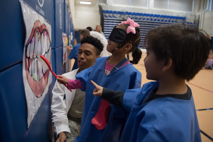 Hanscom Primary School kindergarteners Penelope Schuler and Nicholas Bass work together to clean the teeth, while Senior Airman Joshua Lightning, 66th Medical Squadron dental technician, looks on during a National Children’s Dental Health Month program in the school’s gym, Feb. 28. Kindergarteners and first- and second-graders participated in games and quizzes designed to promote better dental health. (U.S. Air Force photo by Jerry Saslav)