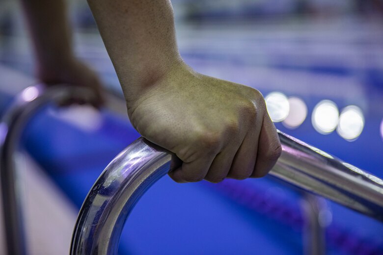 A swimmer grabs the rails to enter the pool at IronWorks Gym, Marine Corps Air Station (MCAS) Iwakuni, Japan, February 16, 2020. The Tsunamis, the MCAS Iwakuni Schools' swim team hosted a friendly swim meet with Ocean Swim team, the local Iwakuni City swim team, in order to foster their friendship in sports. (U.S. Marine Corps photo by Lance Cpl. Triton Lai)