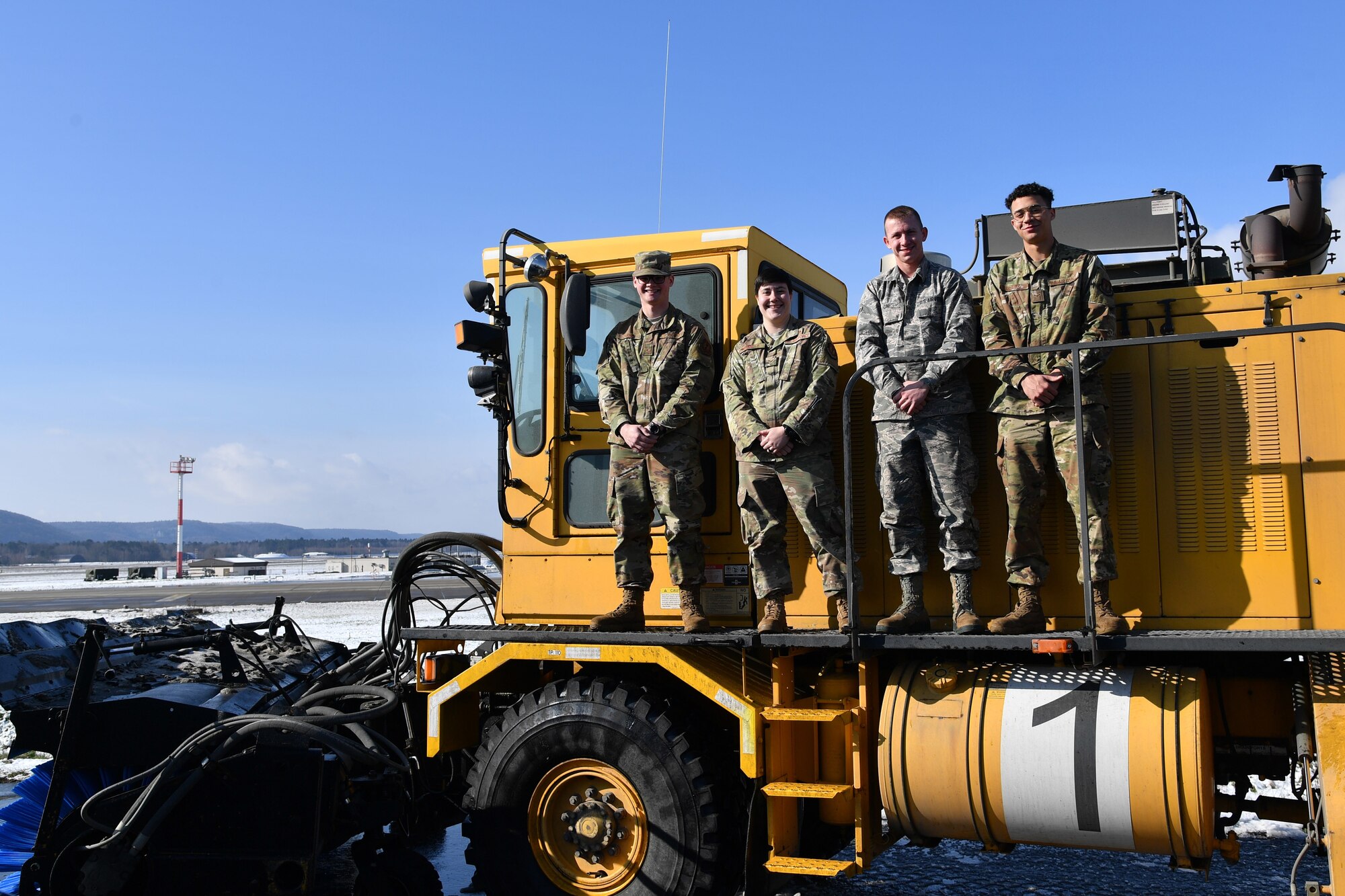 U.S. Air Force Airman Noah Carney, left, Senior Airman Amber Ingalls, Airman 1st Class Charles Zine and Airman 1st Class Ronald Williamson, 786th Civil Engineer Squadron pavements and equipment operators, pose for a photo on an Oshkosh Snow Broom snow removal vehicle at Ramstein Air Base, Germany, Feb. 28, 2020.