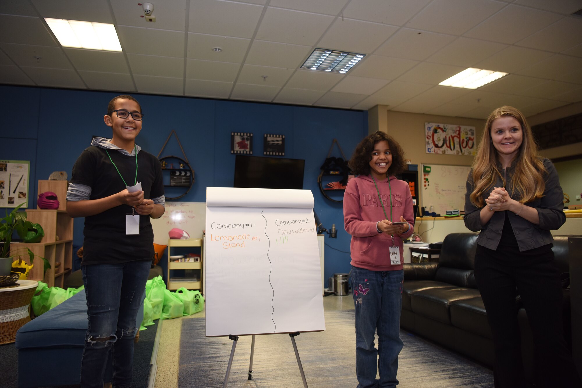 Knox Jasmin (left) and Laila Jasmin, son and daughter of U.S. Army Staff Sgt. Gaetan Jasmin, 21st Theater Sustainment Command transportation manager, stand in front of their classmates as they presented a mock company during the “Youth Saves Event,”at Ramstein Air Base, Germany, Feb. 25, 2019. They presented their companies, a lemonade stand and a dog-walking company, respectively, and asked their classmates if they would invest in their company. The instructors reminded the classmates before they voted for one company or the other what the pros and cons of each were. Through this kind of example the students learned the importance of understanding the companies they might invest in later in life. (U.S. Air Force photo by Senior Airman Kristof J. Rixmann)