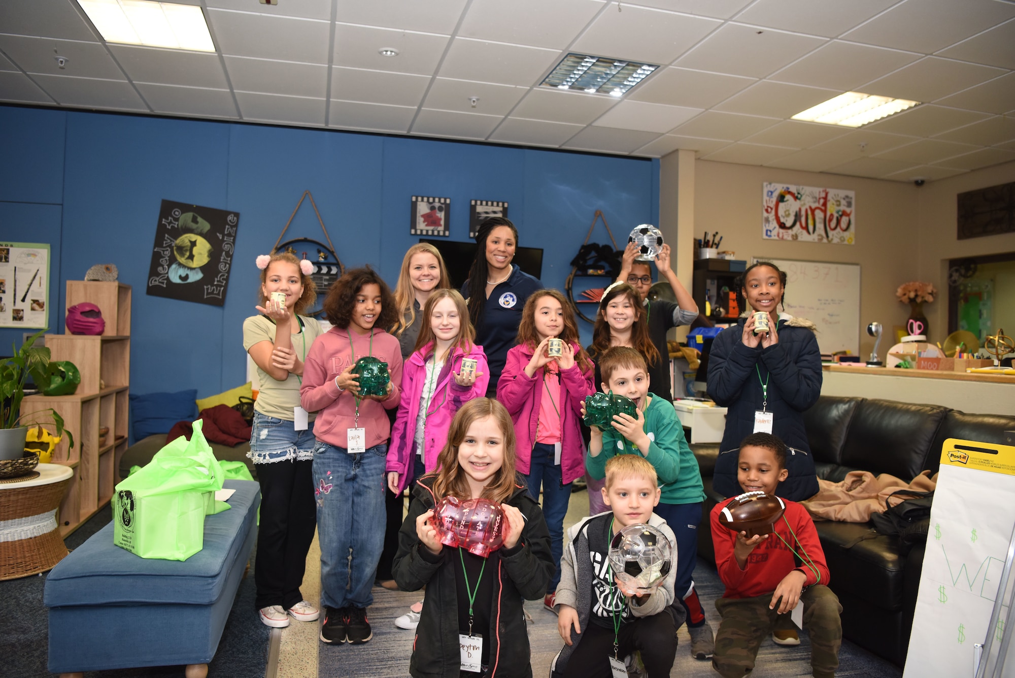 Children attending the “Youth Saves Event '' pose for a photo with their new piggy-banks, alongside their guest teachers who taught a course on money management at Ramstein Air Base, Germany, Feb. 25, 2019. Angelica Williams, 86th Force Support Squadron Airman and Family Readiness Center community readiness consultant said if she can show her students the importance of money early on, they may also realize the power of being debt-free later in their life. (U.S. Air Force photo by Senior Airman Kristof J. Rixmann)