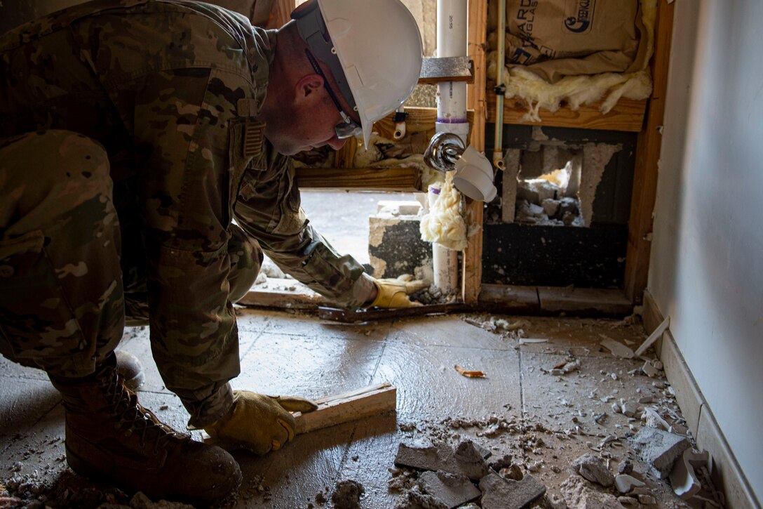 Photo of an Airman picking up rubble during a natural disaster response exercise.