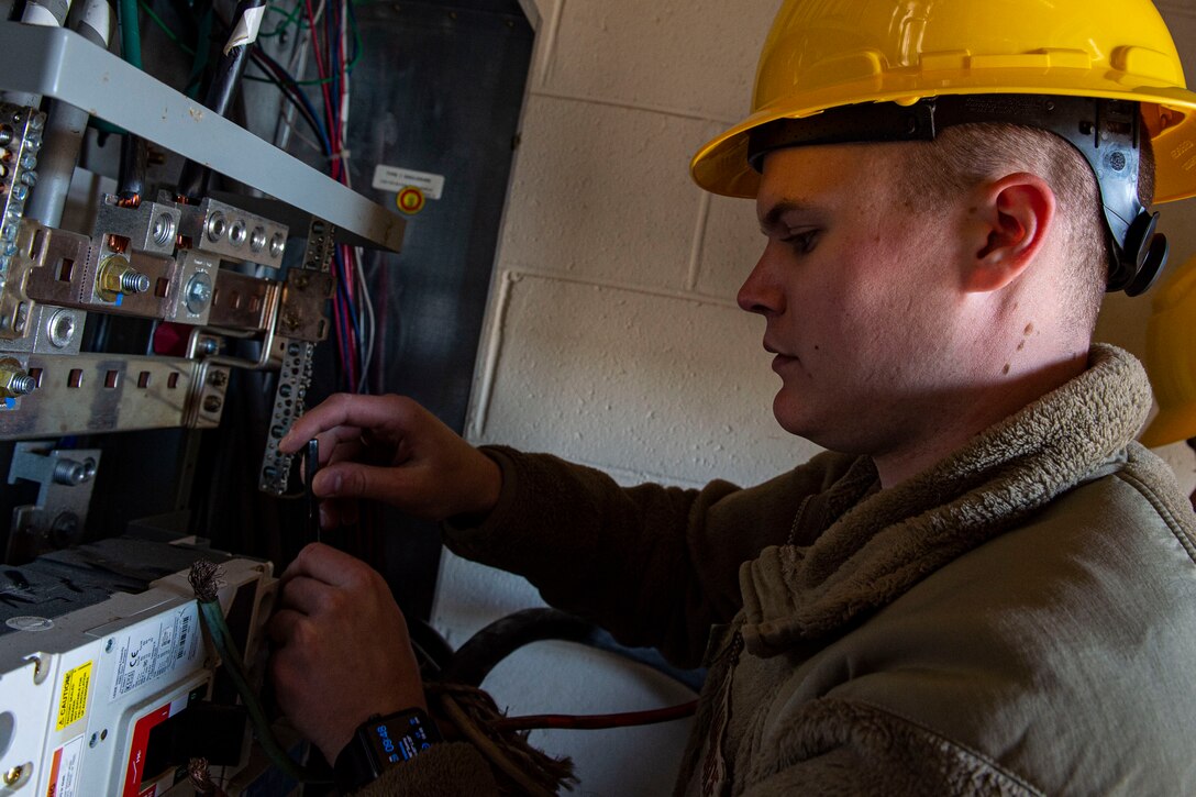 Photo of an Airman connecting wires to a circuit breaker during a natural disaster response exercise.