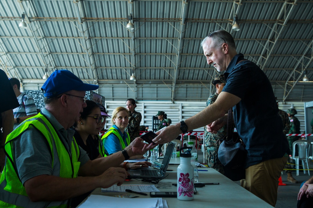 A Thai government official receives a simulated noncombatant evacuee’s passport during a noncombatant evacuation operation as part of Exercise Cobra Gold 2020 at Utapao, Kingdom of Thailand, Feb. 29.