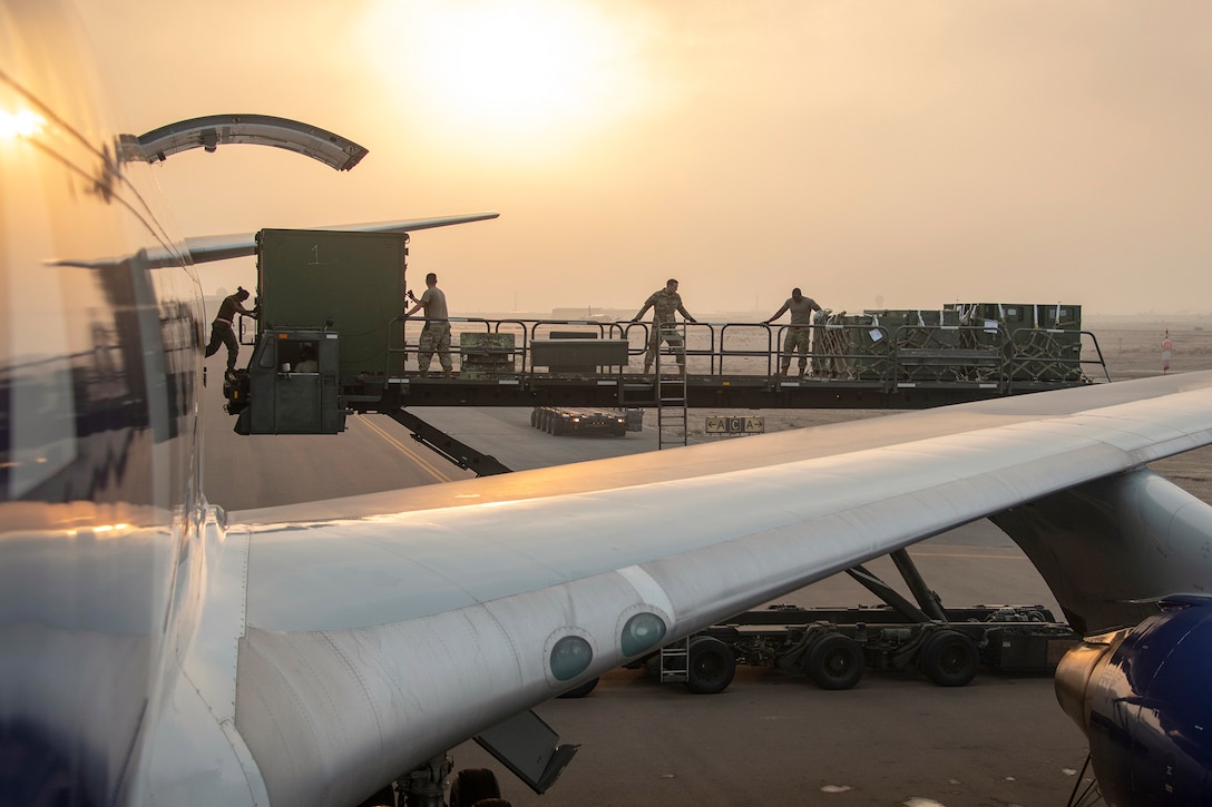 Marines, airmen and sailors, shown in silhouette, unload