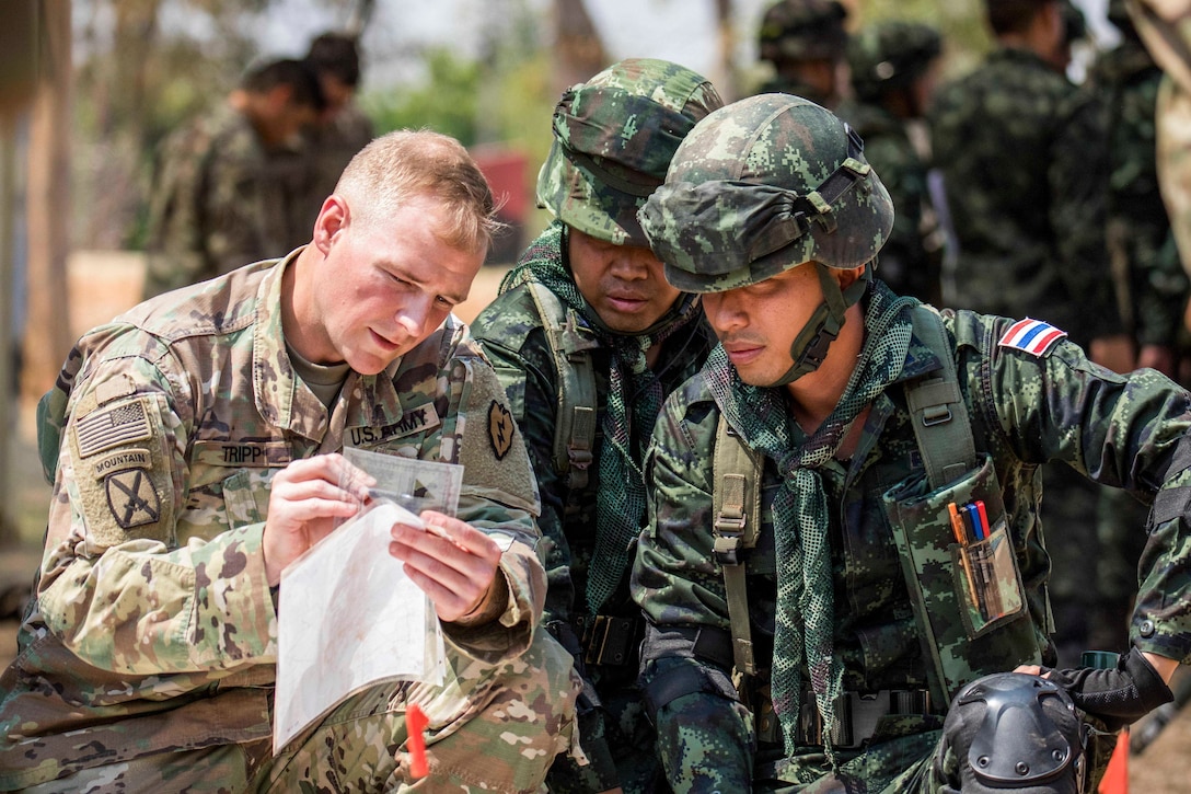 A U.S. solider holds up papers that he and two Thai counterparts examine.