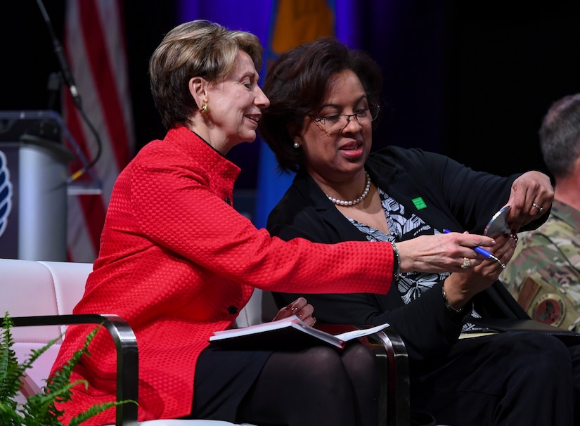 Secretary of the Air Force Barbara Barrett and Toni Townes-Whitley, U.S. Regulated Industries president, look at a magnetic coaster created by U.S. Air Force Tech. Sgt. Daniel Caban, 1st Aircraft Maintenance Squadron crew chief, during the Spark Tank competition in Orlando, Florida, Feb. 28, 2020.