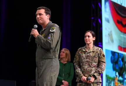 U.S. Air Force Maj. Andrew Van Timmeren, 1st Fighter Wing F-22 Raptor pilot, and 1st Lt. Marlene Myers, 1st FW maintenance officer,  highlight the Portable Magnetic Aircraft Covers during the Spark Tank competition in Orlando, Florida, Feb. 28, 2020.