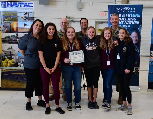 Col. keith Ward stands for an award photo with the winning students.