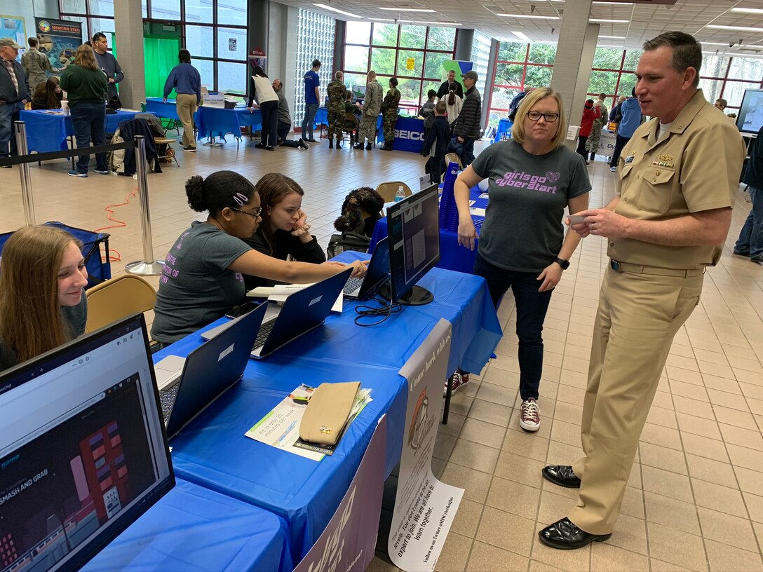 IMAGE: SPOTSYLVANIA, Va. (Feb. 29, 2020) – Capt. Casey Plew, Naval Surface Warfare Center Dahlgren Division (NSWCDD) commanding officer, talks with 
members of the Spotsylvania High School’s Girls Go CyberStart group at the annual science, technology, engineering, mathematics (STEM) Summit hosted by Chancellor High School. Plew was among the NSWCDD leaders, scientists and engineers who joined a myriad of organizations to engage students with science, technology, engineering, mathematics (STEM) demonstrations. “By the end of Girls Go CyberStart, students will have delved into disciplines such as cryptography, digital forensics and open source intelligence gathering and more,” according to the organization’s website. “The program gets increasingly difficult, but the first stage is designed to be accessible to anyone to uncover hidden superstars with natural ability.” 
(U.S. Navy photo/Released)
