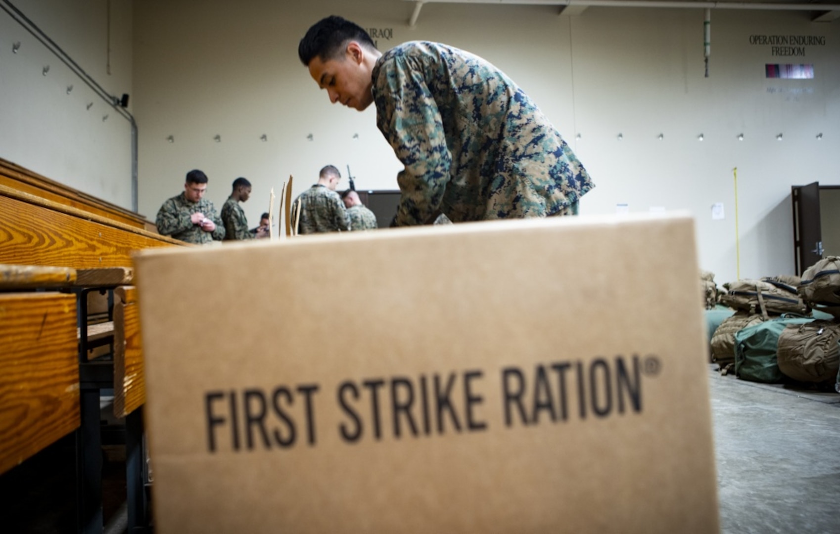 Marine stands next to meal ration box.
