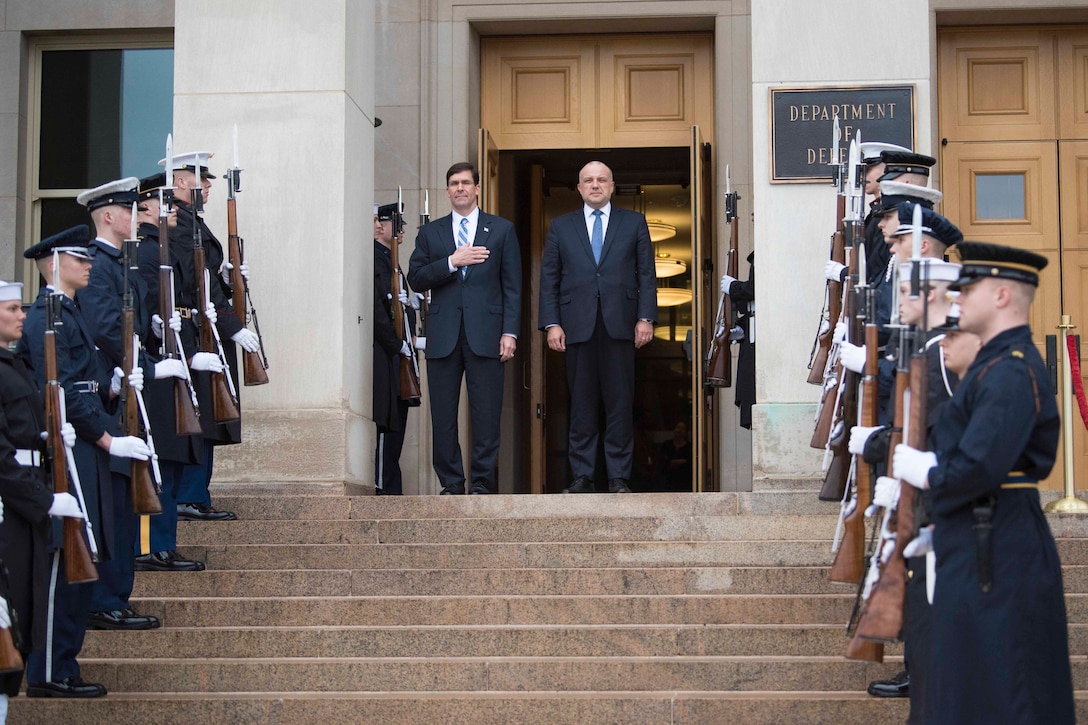 Defense Secretary Dr. Mark T. Esper stands next to a man at the steps with service members on either side.