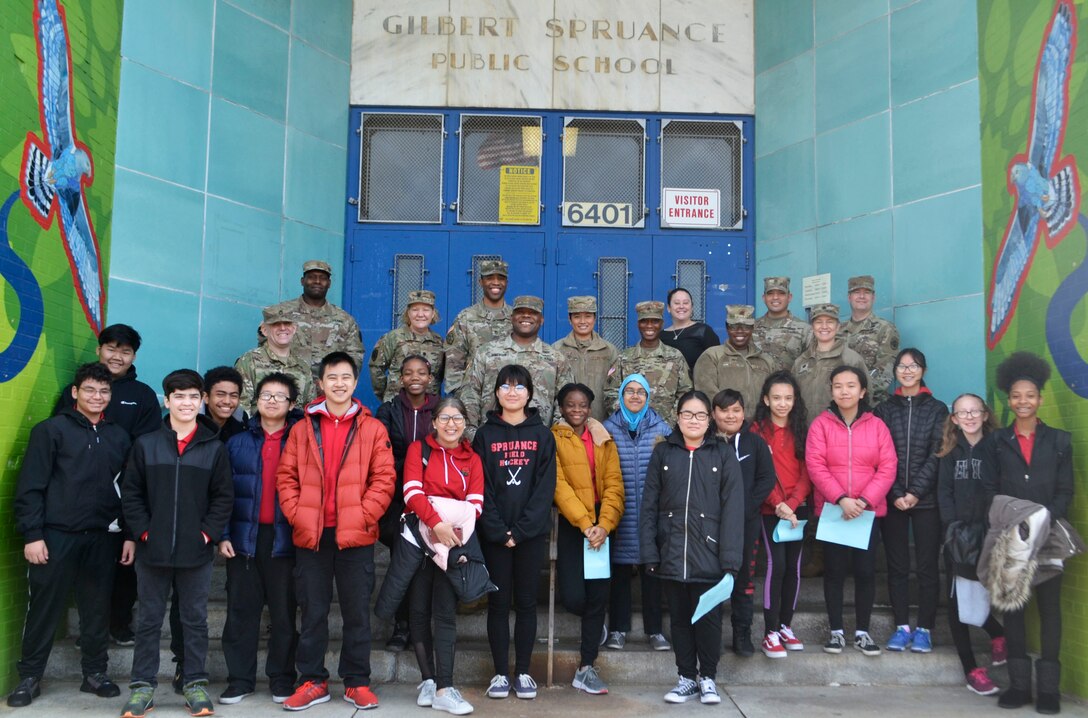 A group of students and active duty military members pose in front of Gilbert Spruance School in Philadelphia on Read Across America Day.