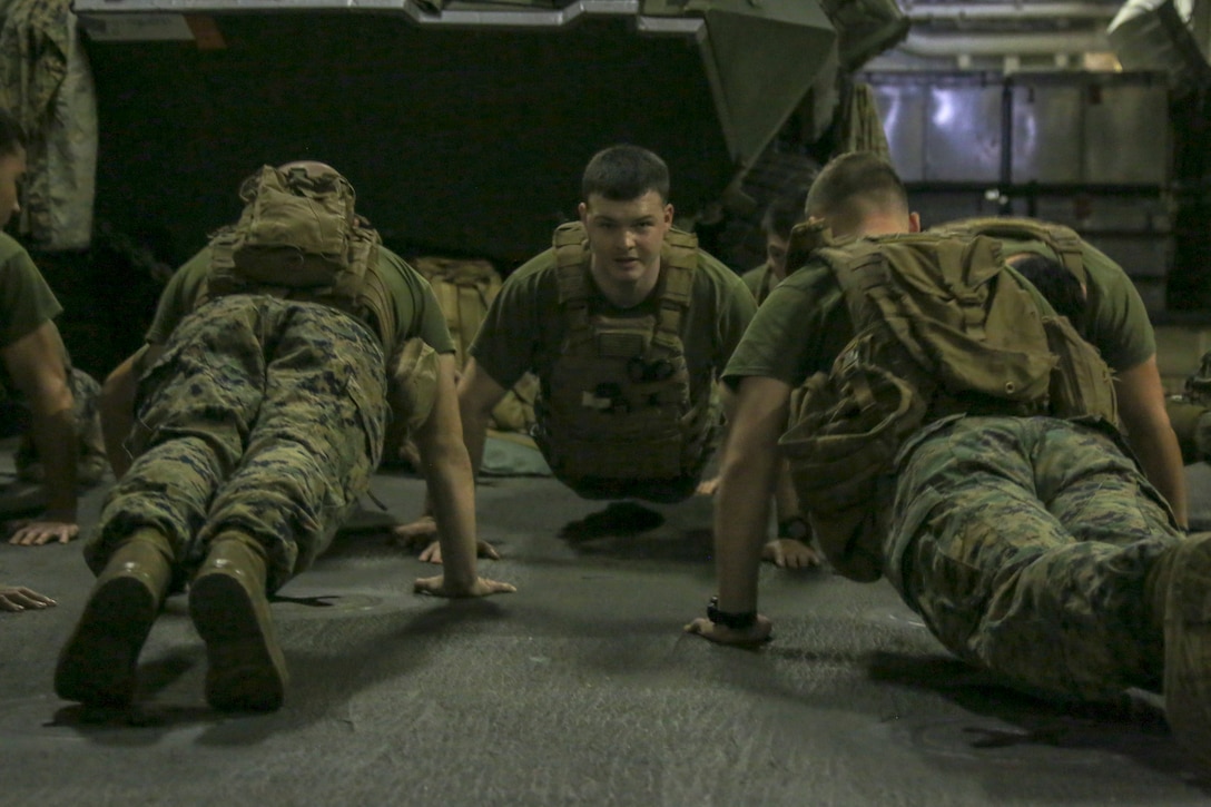 200207-M-IR130-2029 U.S. 5TH FLEET AREA OF OPERATIONS (Feb. 7, 2020) Marines assigned to Fox Company, Battalion Landing Team, 2nd Battalion, 8th Marine Regiment, 26th Marine Expeditionary Unit (MEU), do push-ups aboard the amphibious assault ship USS Bataan (LHD 5). Bataan Amphibious Ready Group, with embarked 26th MEU, is deployed to the U.S. 5th Fleet area of operations in support of maritime security operations to reassure allies and partners and preserve the freedom of navigation and the free flow of commerce in the region. (U.S. Marine Corps photo by Lance Cpl. Gary Jayne III)