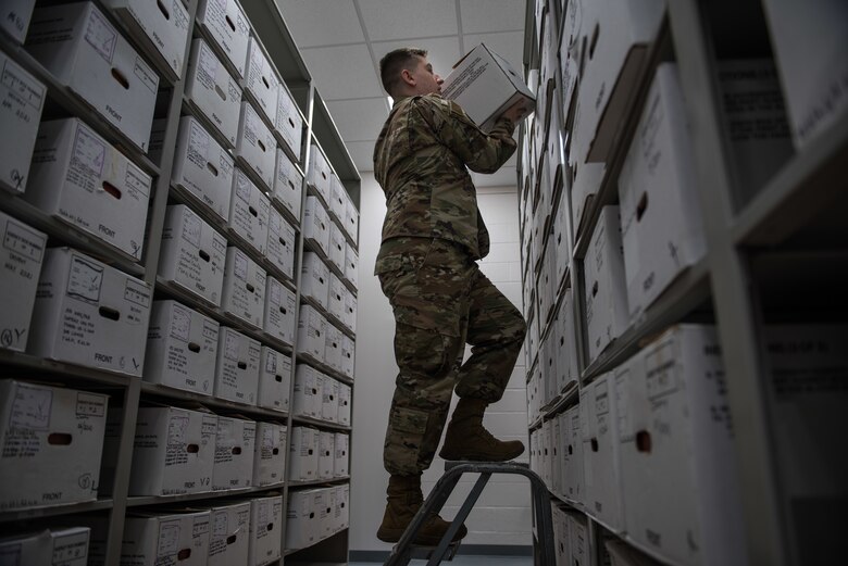 A U.S. Air Force Airman stores records on a shelf.