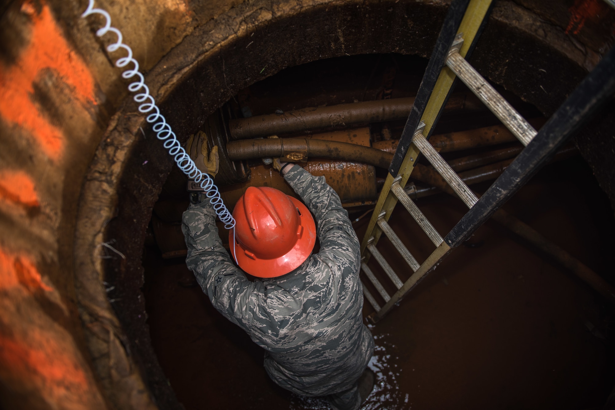 A U.S. Air Force Airman works in a manhole.