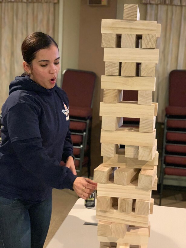 Airman 1st Class Mabell Teixeira of the 104th Force Support Squadron removes a game piece from the Jenga tower with intense concentration during the 104th Fighter Wing’s 2nd annual Officer vs. Enlisted Olympic games, Feb. 1, 2020. The enlisted and the officers took part in a friendly competition as part of the Wing’s camaraderie with the final score of enlisted 14 officers 13. (U.S. Air National Guard photo by Senior Master Sgt. Julie Avey)