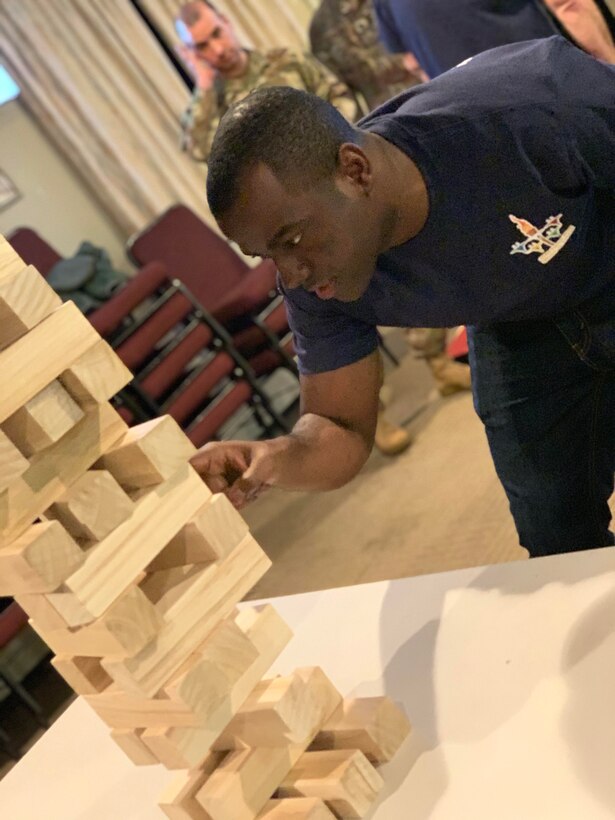 Staff Sgt. Shemron Ross of the 104th Force Support Squadron removes a game piece from the Jenga tower with intense concentration during the 104th Fighter Wing’s 2nd annual Officer vs. Enlisted Olympic games, Feb. 1, 2020. The enlisted and the officers took part in a friendly competition as part of the Wing’s camaraderie with the final score of enlisted 14 officers 13. (U.S. Air National Guard photo by Senior Master Sgt. Julie Avey)