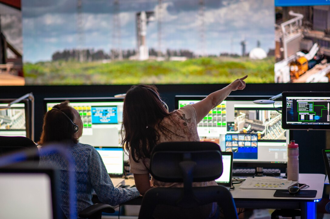 Woman at console points outside control tower.