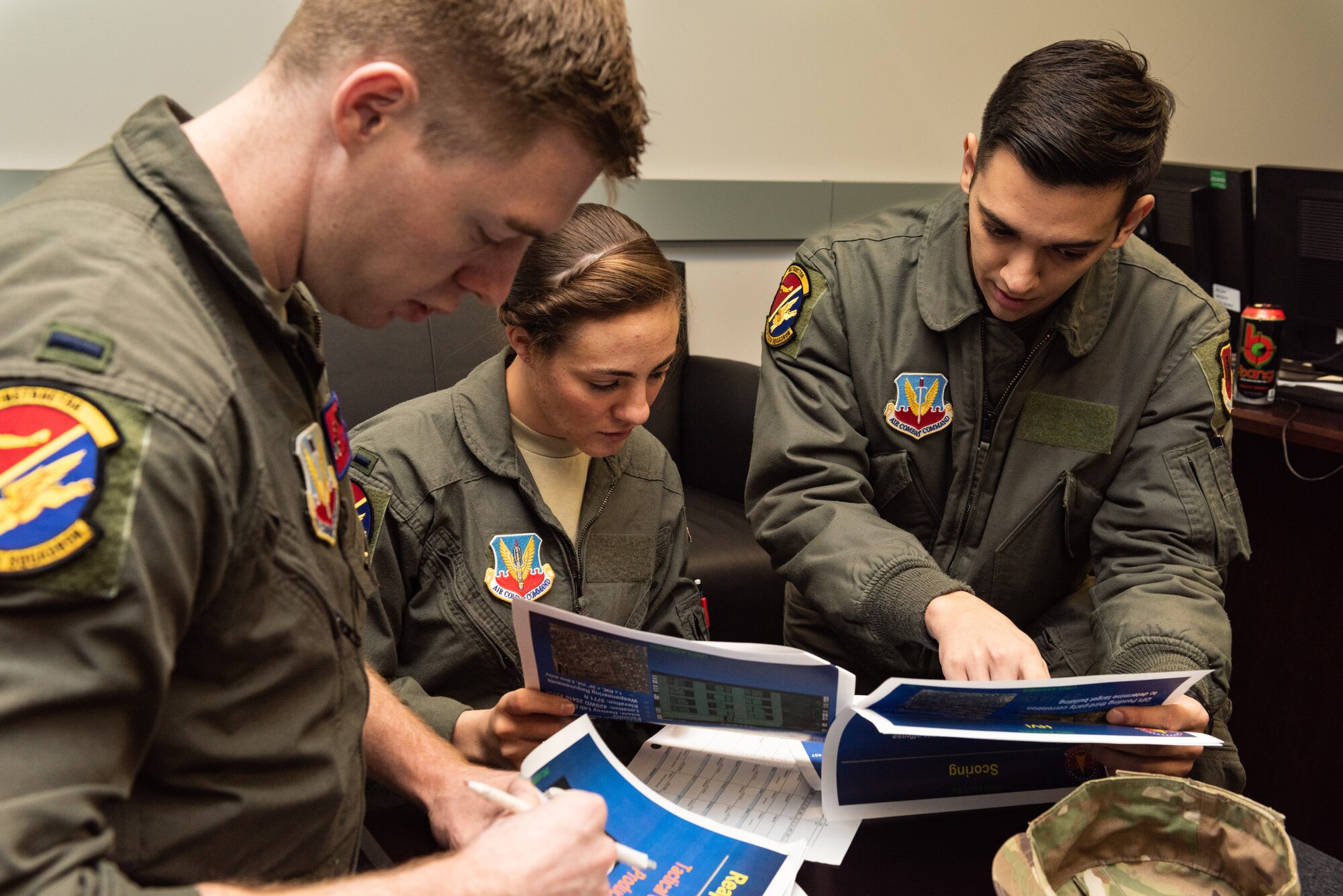 Three Airmen review tactical strategies on paper.