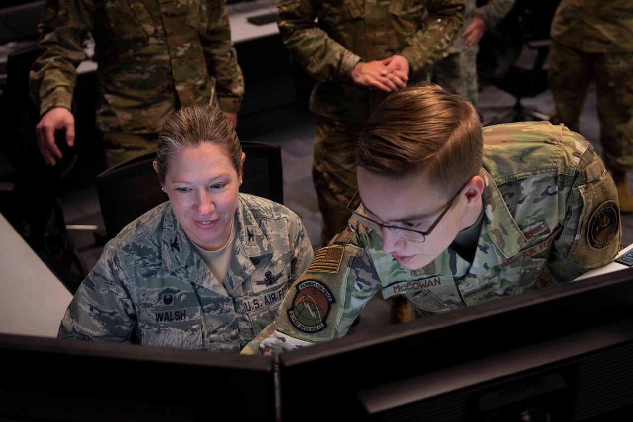 A young airman points to an image on a computer screen.