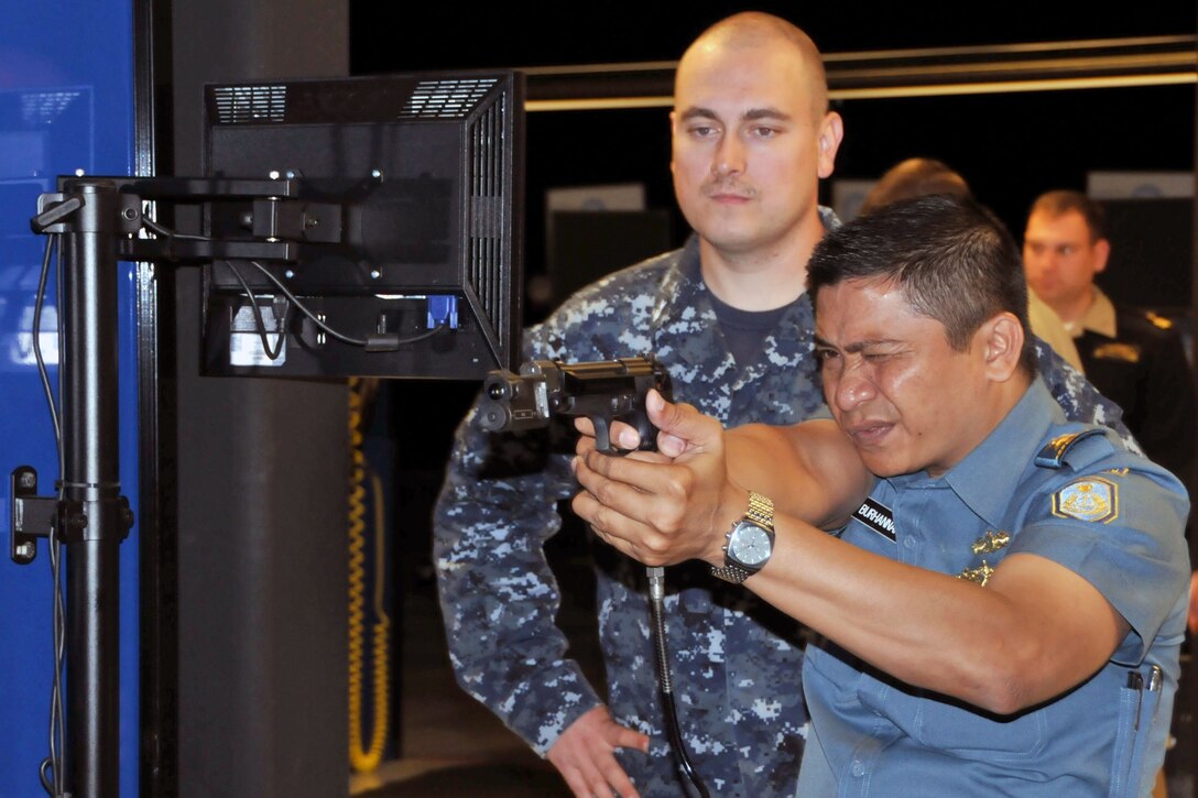 A foreign service member aims a pistol while another watches.