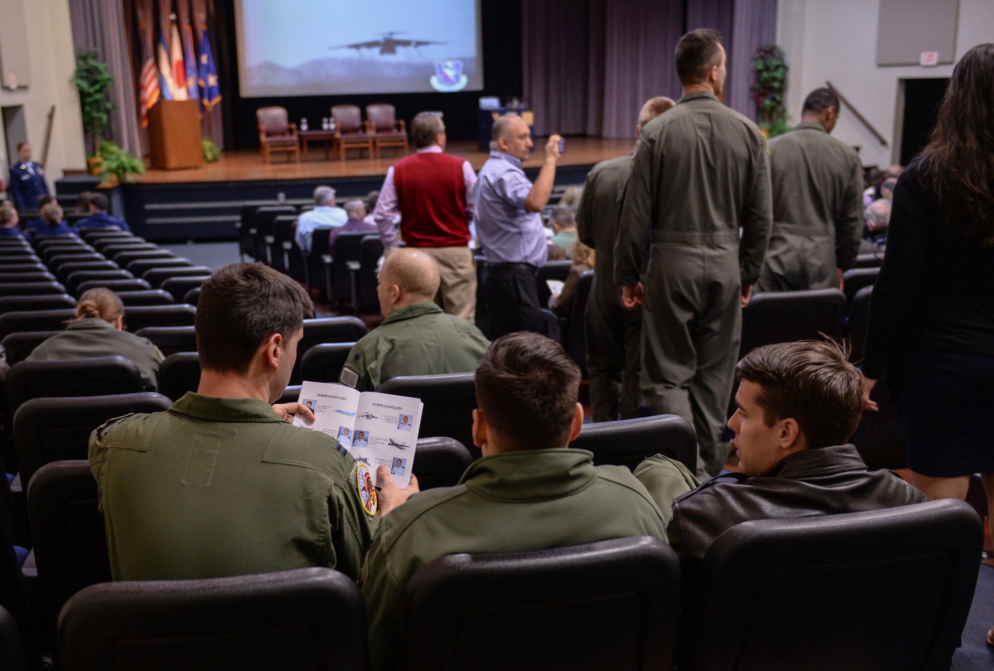Three 14th Flying Training Wing instructor pilots look at a guide prior to the graduation ceremony of Specialized Undergraduate Pilot Training Class 20-08/09 Feb. 28, 2020, at Columbus Air Force Base, Miss. Instructor pilots go to the ceremony to show support to the students they helped train. (U.S. Air Force photo by Airman Davis Donaldson)