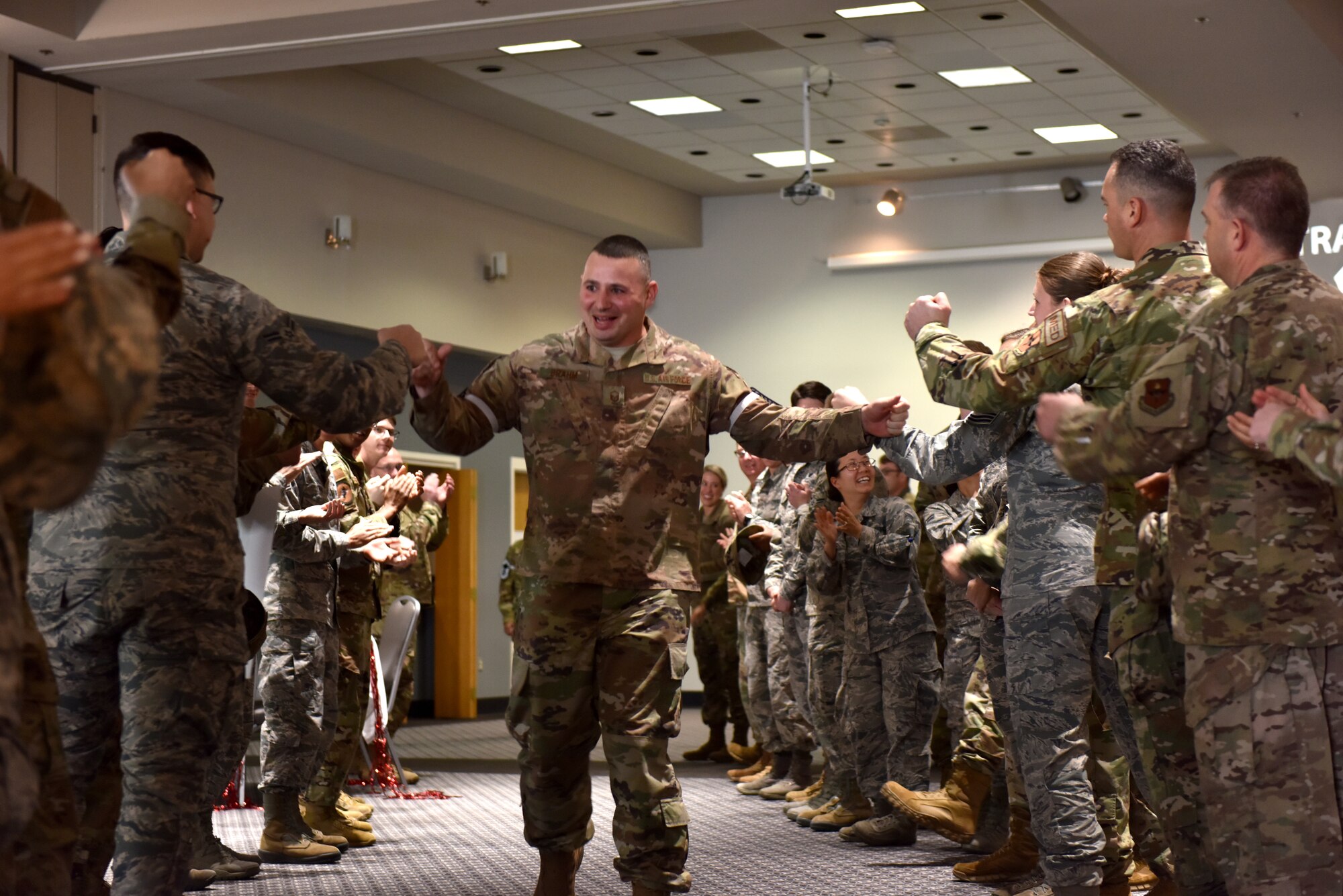 U.S. Air Force Senior Master Sgt. select John Brahm, 17th Communications Squadron flight chief, runs through an aisle of supporters, coworkers and family during the Senior Master Sgt. release party at the event center on Goodfellow Air Force Base, Texas, March 3, 2020. The aisle allowed everyone to fist bump and high-five the selectees before they received their certificates. (U.S. Air Force photo by Senior Airman Seraiah Wolf)