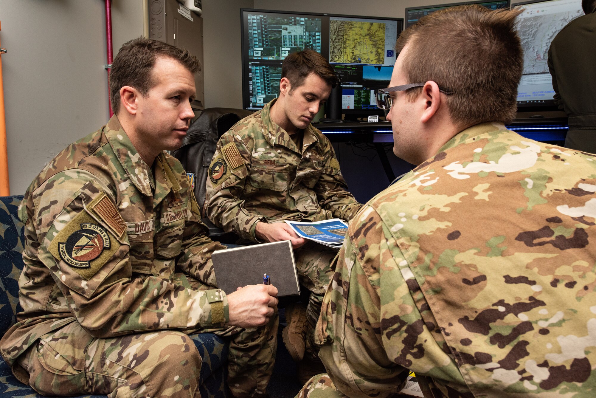 17th Special Tactics Squadron Airmen talk in a group with notebooks in hand