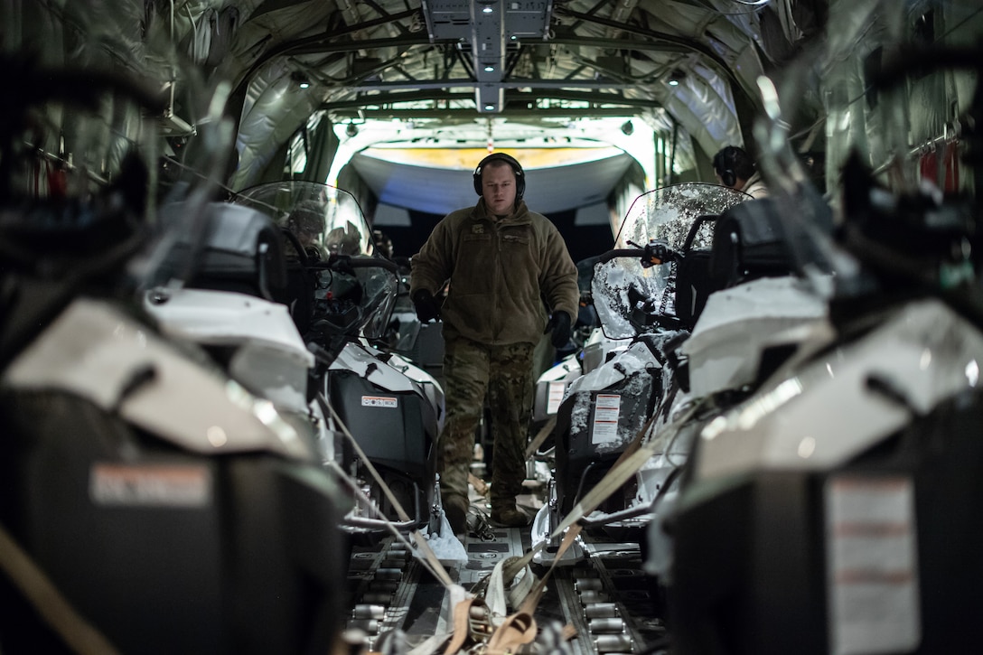 U.S. Air Force flying crew chief navigates through snowmobiles aboard a C-130J Super Hercules at an airport in Kiruna, Sweden, prior to Exercise Cold Response 20, Feb. 27.
