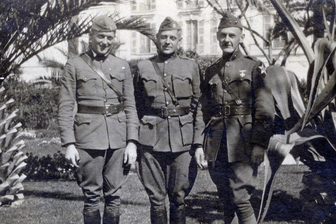 Two army soldiers and a marine in uniform near palm trees