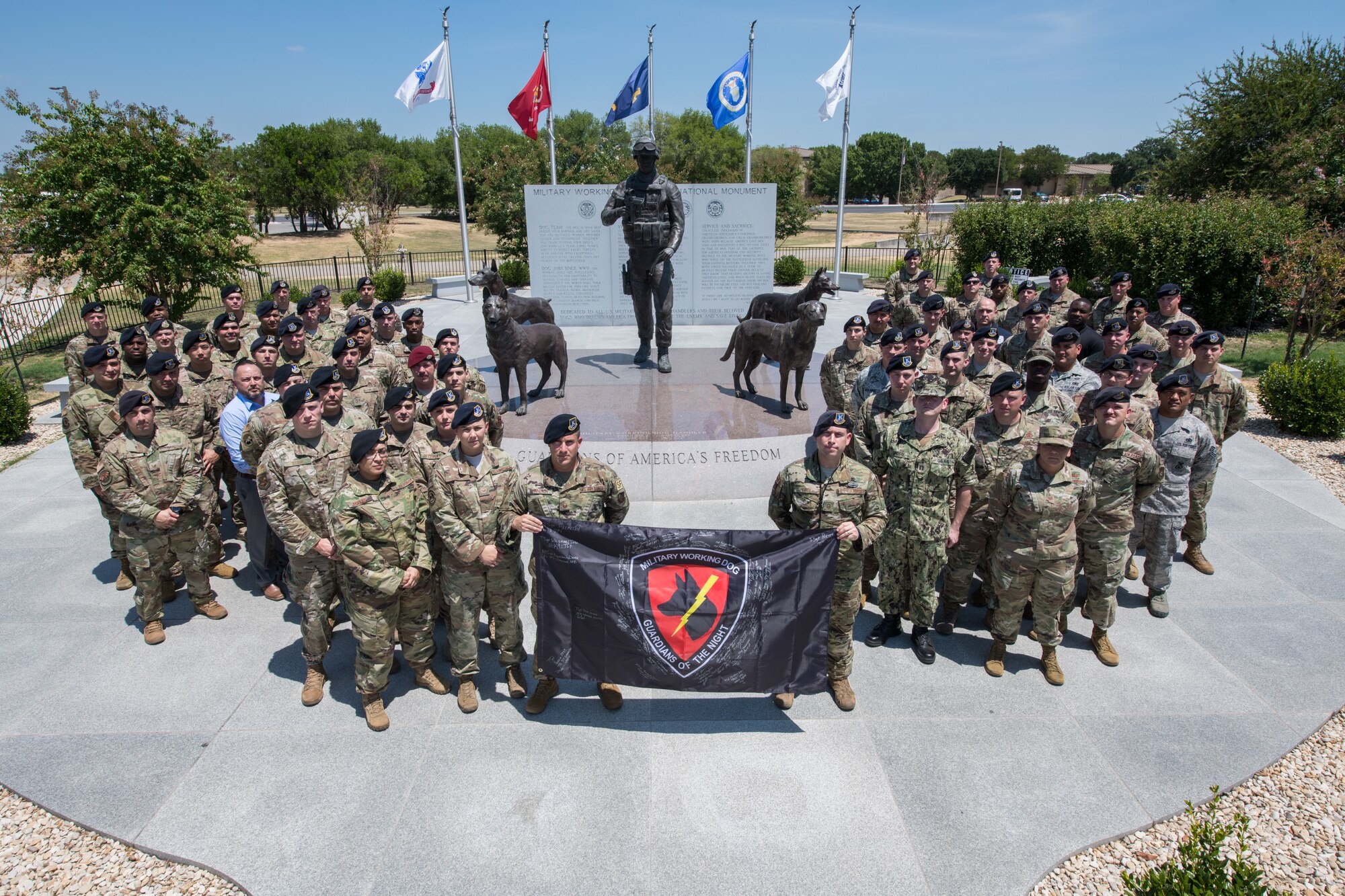 U.S. Air Force Security Forces Kennel Masters pose for a group photo in front of the Military Working Dog (MWD) monument Aug. 13, 2019, at Joint Base San Antonio-Lackland, Texas. The members gathered at Joint JBSA-Lackland this week for the first USAF Military Working Dog Kennel Master's Workshop. This multi-domain initiative will aid in reconstituting MWD efforts by restoring lethality to Security Forces through training and development. As an effort to reconstitute Defenders this training opportunity allows for the professional development of MWD personnel, dissemination of mandated information, cross talk on important matters in the career field, to bring in subject matter experts that affect the MWD Program and encourage professional networking. The conference directly supports and enhances Security Forces mission essential tasks to support the Military Working Dog program by building force proficiency and streamlining productivity similar to the collaborative efforts of our sister services. (U.S. Air Force photo by Sarayuth Pinthong)