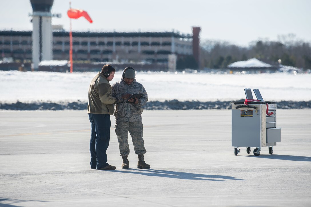 Crew chiefs assigned to the 158th Maintenance Group, 158th Fighter Wing, Vermont Air National Guard, work on a mobile device on the flight line.